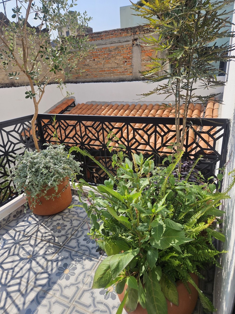 Terraza de Casa Mestiza con piso de talavera, herrería geométrica y macetas de barro